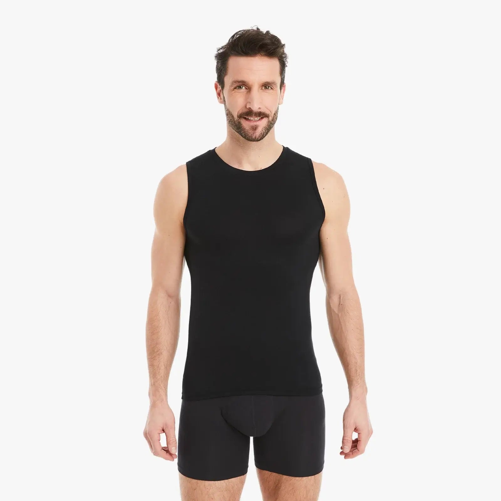 Ein selbstbewusster Mann trägt ein schwarzes Ärmelloses Unterhemd mit Rundhalsausschnitt. Das Shirt besteht aus Micro-Modal Stoff, bietet einen Slim-Fit Schnitt und verspricht hervorragenden Tragekomfort. Der Mann schaut selbstbewusst und direkt in die Kamera. #farbe_schwarz