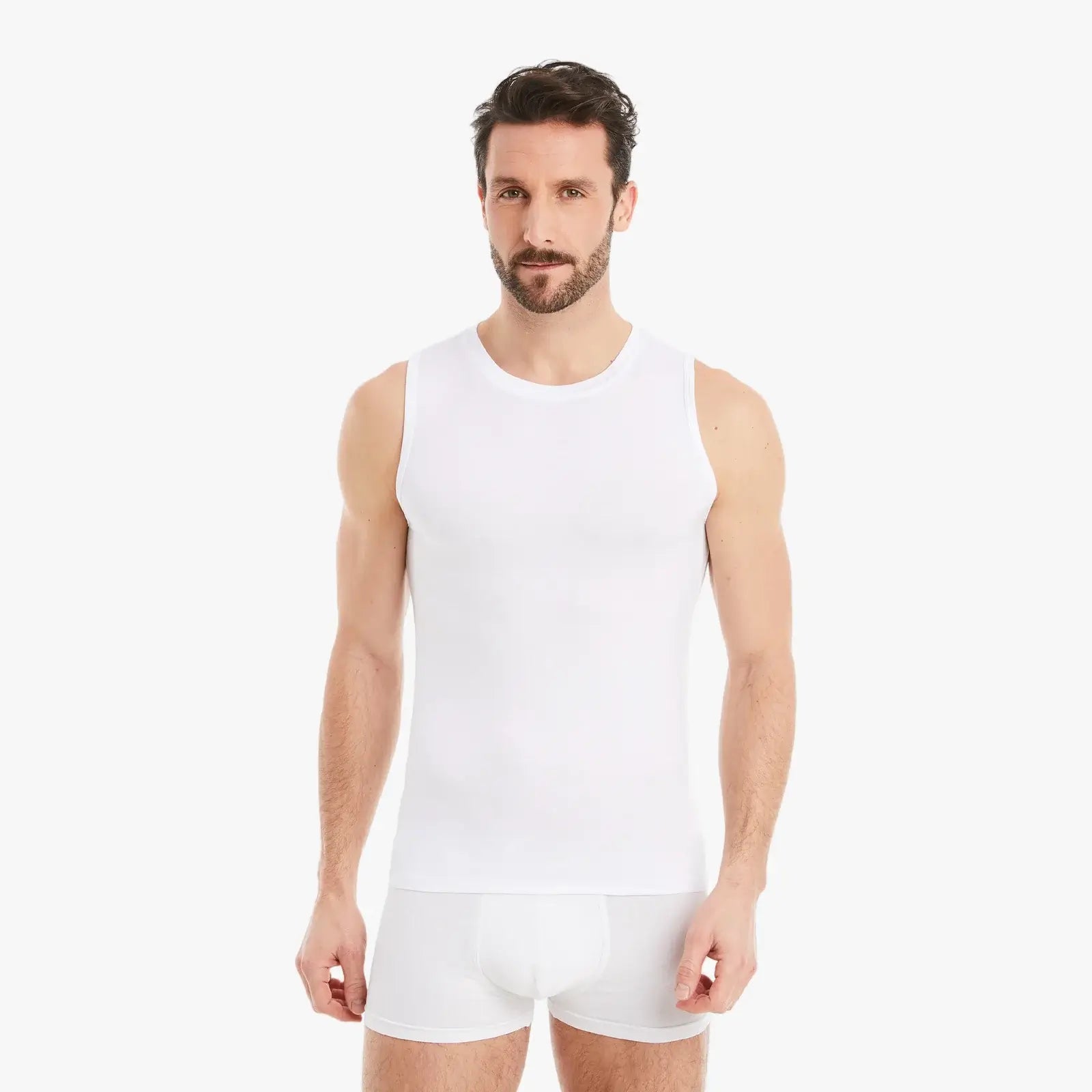 Ein selbstbewusster Mann trägt ein ärmelloses, weißes Herren Unterhemd mit Rundhals und schaut entspannt in die Kamera. Das Shirt besteht aus Micro-Modal Stoff, bietet einen Slim-Fit Schnitt und verspricht höchsten Tragekomfort. #farbe_weiß