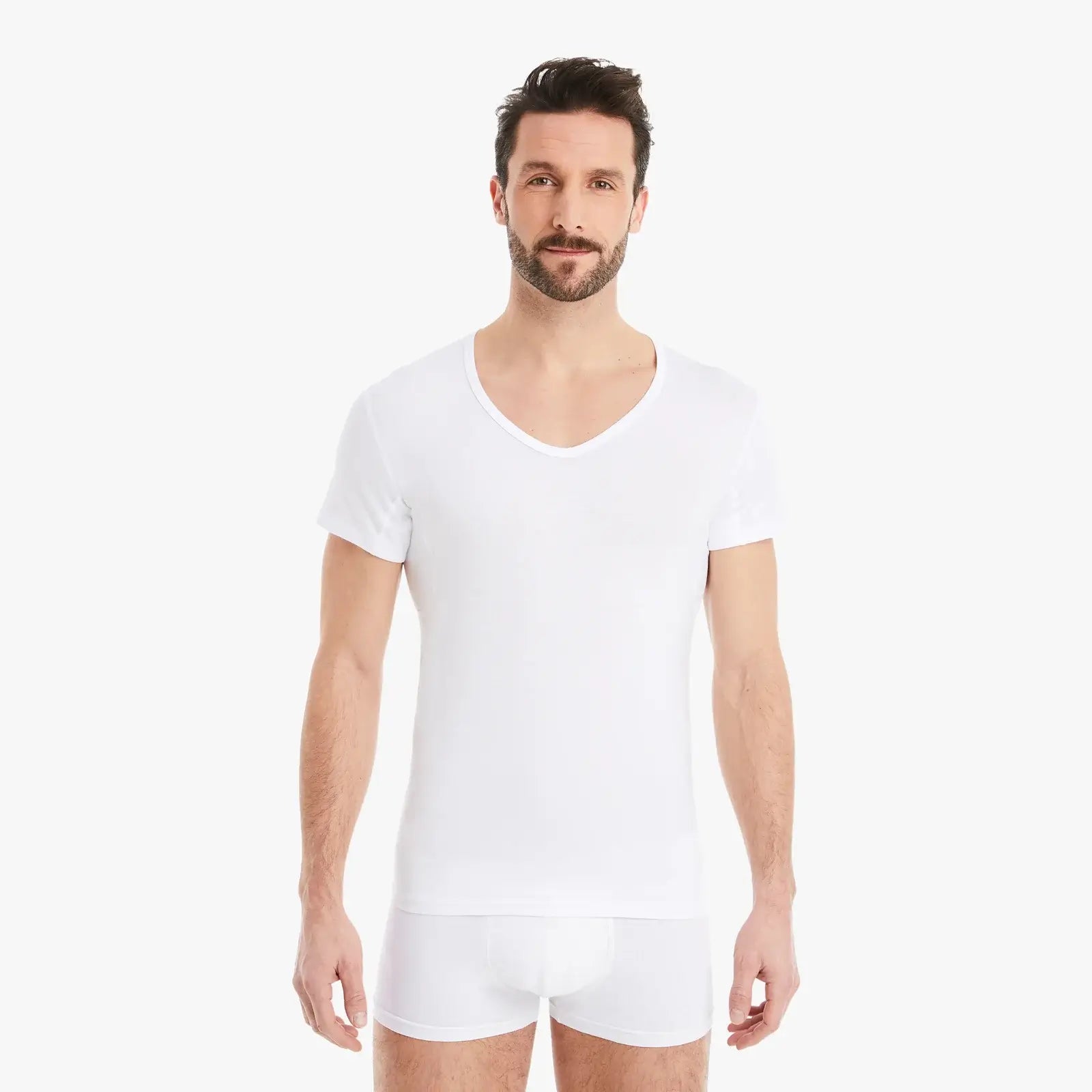 Selbstbewusster Mann mit weißem Funktionsunterhemd Herren mit Einsätzen. Reduziert Schweißflecken, Slim-Fit Schnitt, hoher Tragekomfort. #farbe_weiß