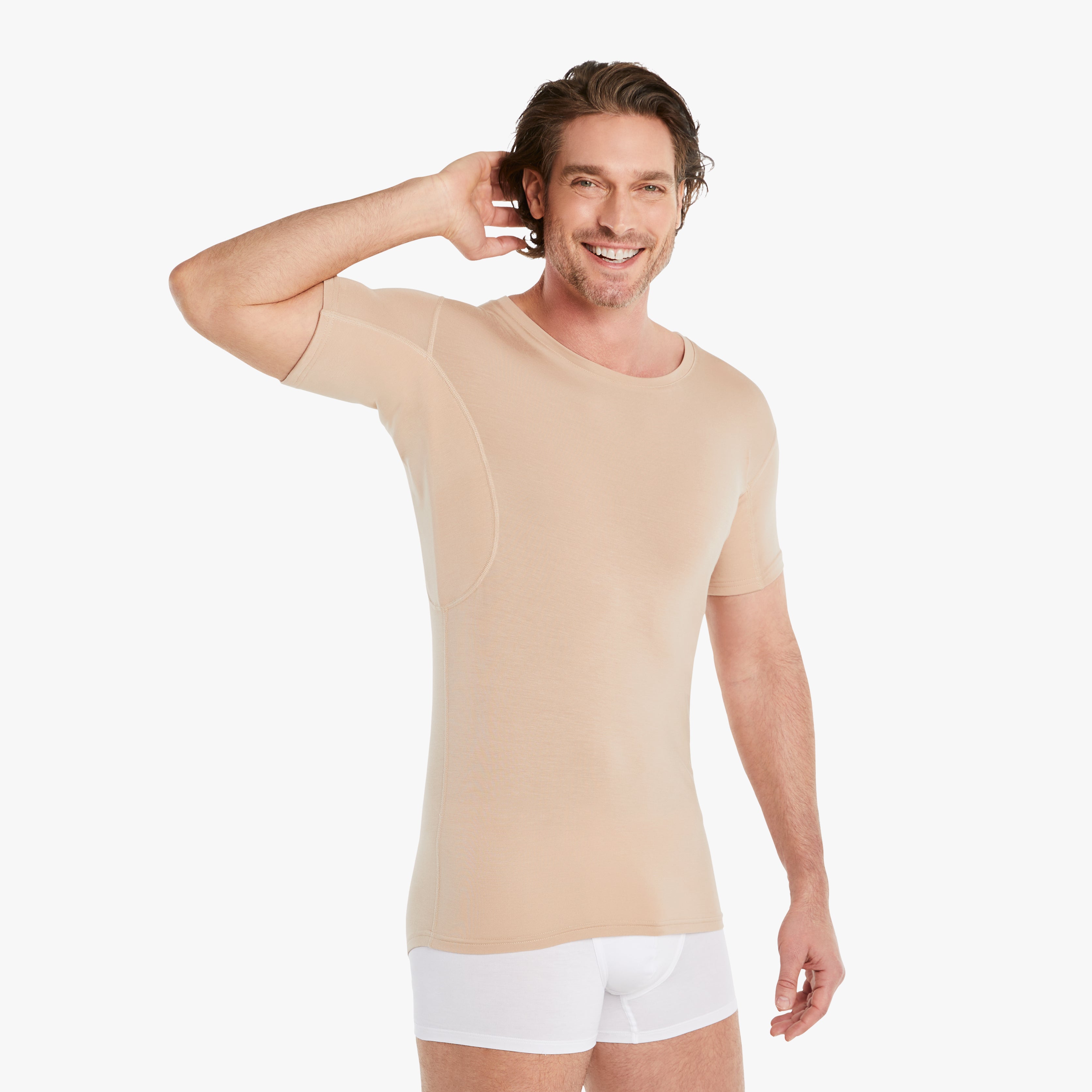 Zufriedener Mann trägt nude Anti-Schweiß Unterhemd Herren mit Rundhals, Größe M. 100% Schutz vor Schweißflecken, innovativer 3-Lagen Technologie. Zertifizierter Tragekomfort, während er lächelnd die Achseln ohne Schweißflecken zeigt. #farbe_nude
