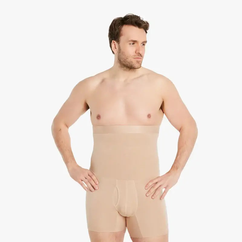 Selbstbewusster Mann trägt hautfarbene Shapewear Kompressions-Shorts für Herren und schaut zur Seite, die Hände an den Hüften. Die Shorts bieten einen extra starken Kompressionseffekt und bestehen aus hochwertiger Baumwolle für maximalen Tragekomfort. #farbe_nude