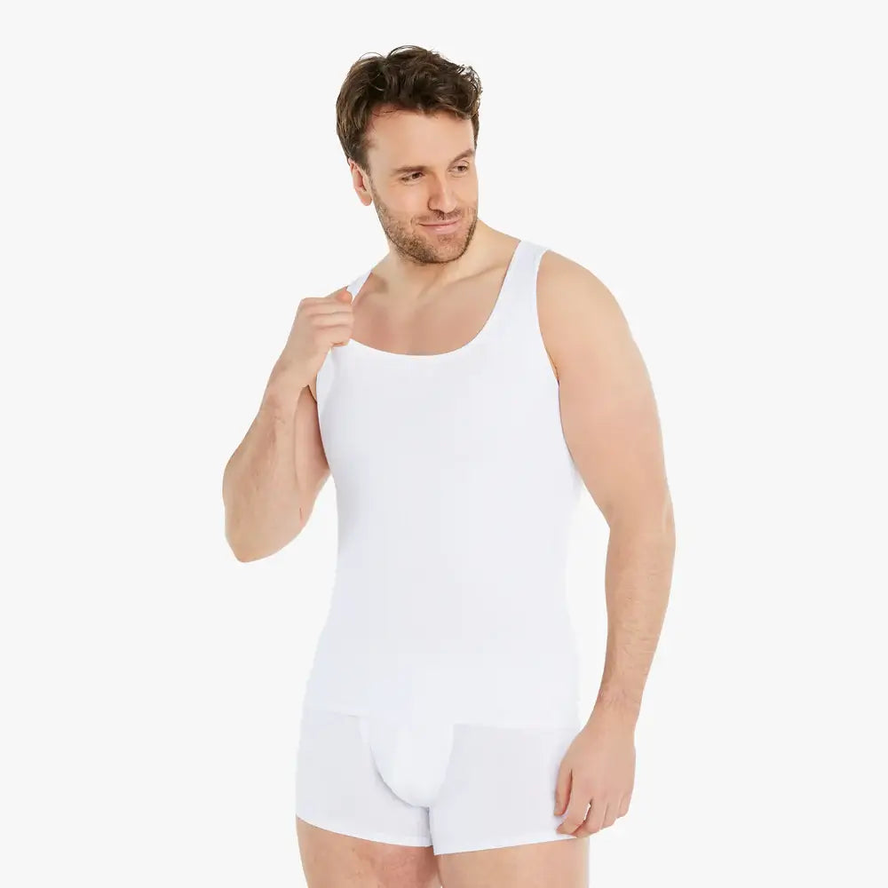 Lächelnder Mann trägt ein weißes Shapewear Kompressions-Unterhemd und schaut zur Seite. Das ärmellose Unterhemd bietet einen starken Bauch-weg-Effekt und besteht aus hochwertiger Baumwolle für maximalen Tragekomfort. #farbe_weiß