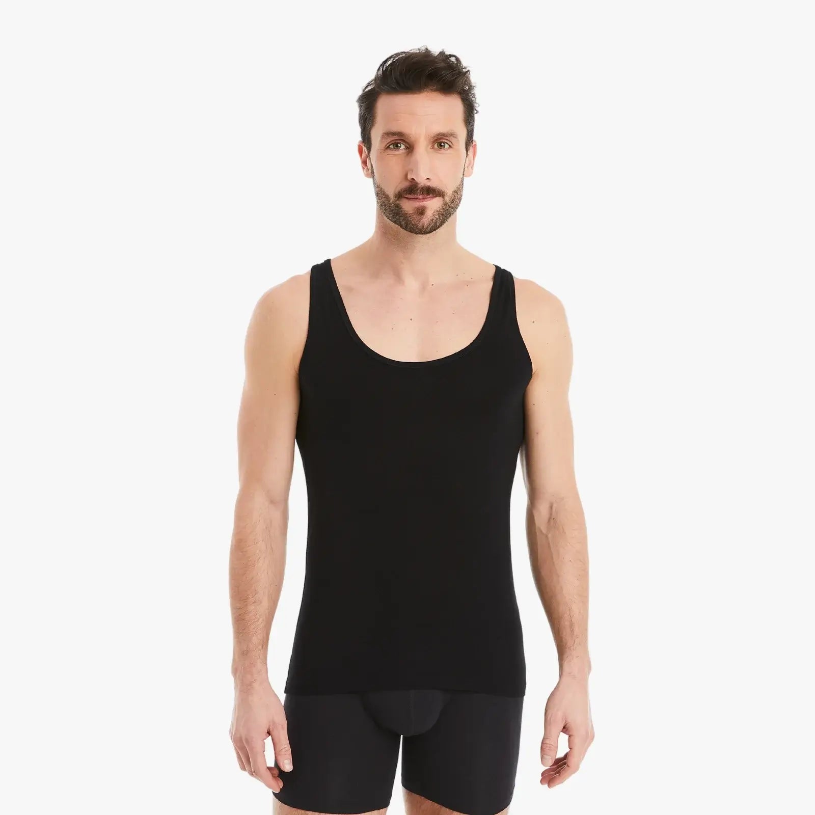 Selbstbewusster Mann mit entspannten Armen seitlich schaut in Kamera. Trägt schwarzes Herren Unterhemd Tank-Top aus Micro-Modal Stoff im Slim Fit. #farbe_schwarz