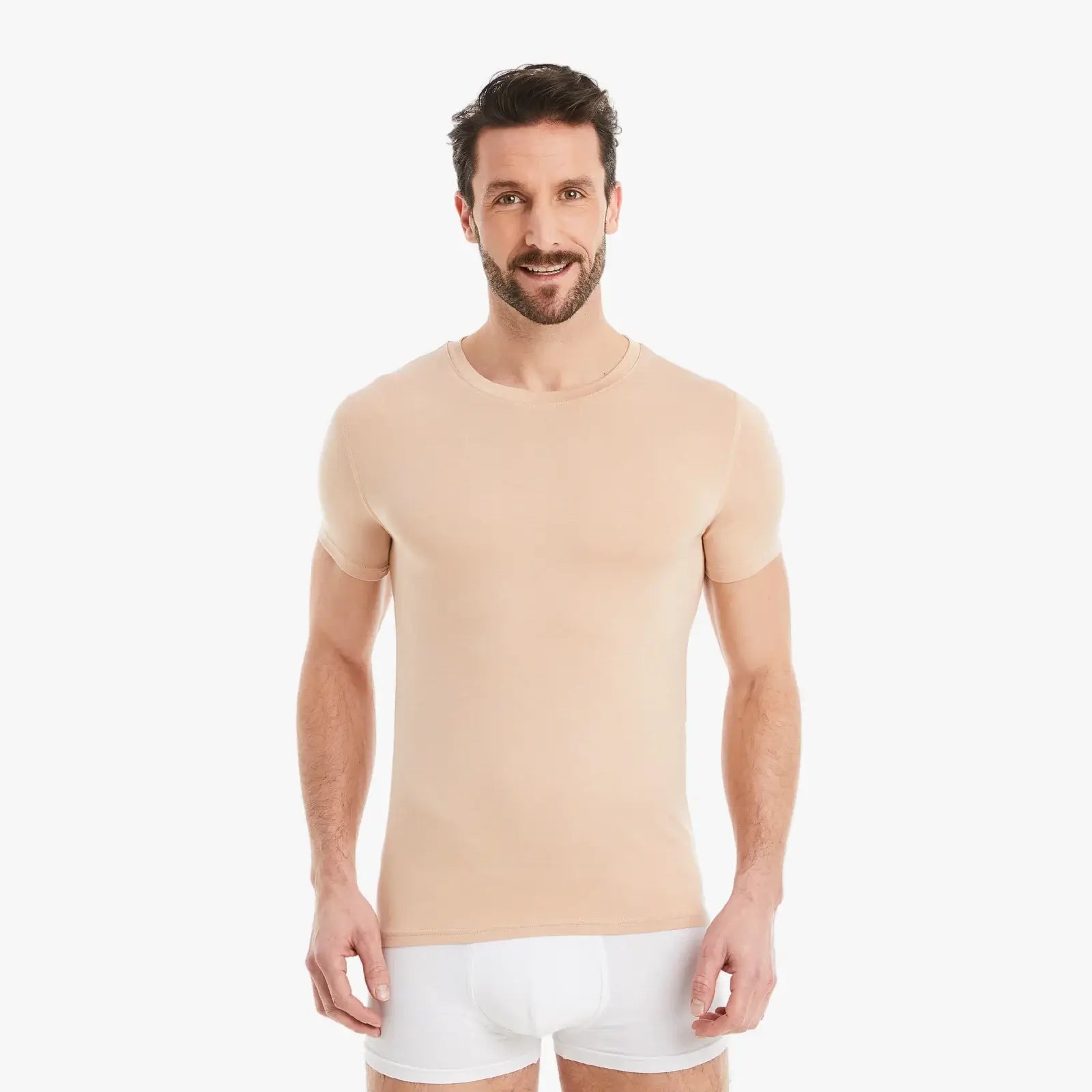 Hautfarbenes Herren Unterhemd Kurzarm Rundhals. Micro-Modal Stoff, hergestellt in Europa, hoher Tragekomfort. Selbstbewusster Mann lächelt selbstbewusst in die Kamera. #farbe_nude