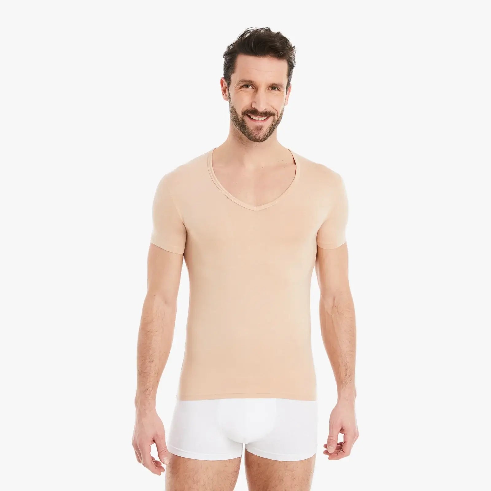 Hautfarbenes Herren Unterhemd Kurzarm V-Ausschnitt. Micro-Modal Stoff, Slim Fit, hoher Tragekomfort. Selbstbewusster Mann lächelt in die Kamera, Arme entspannt seitlich. #farbe_nude