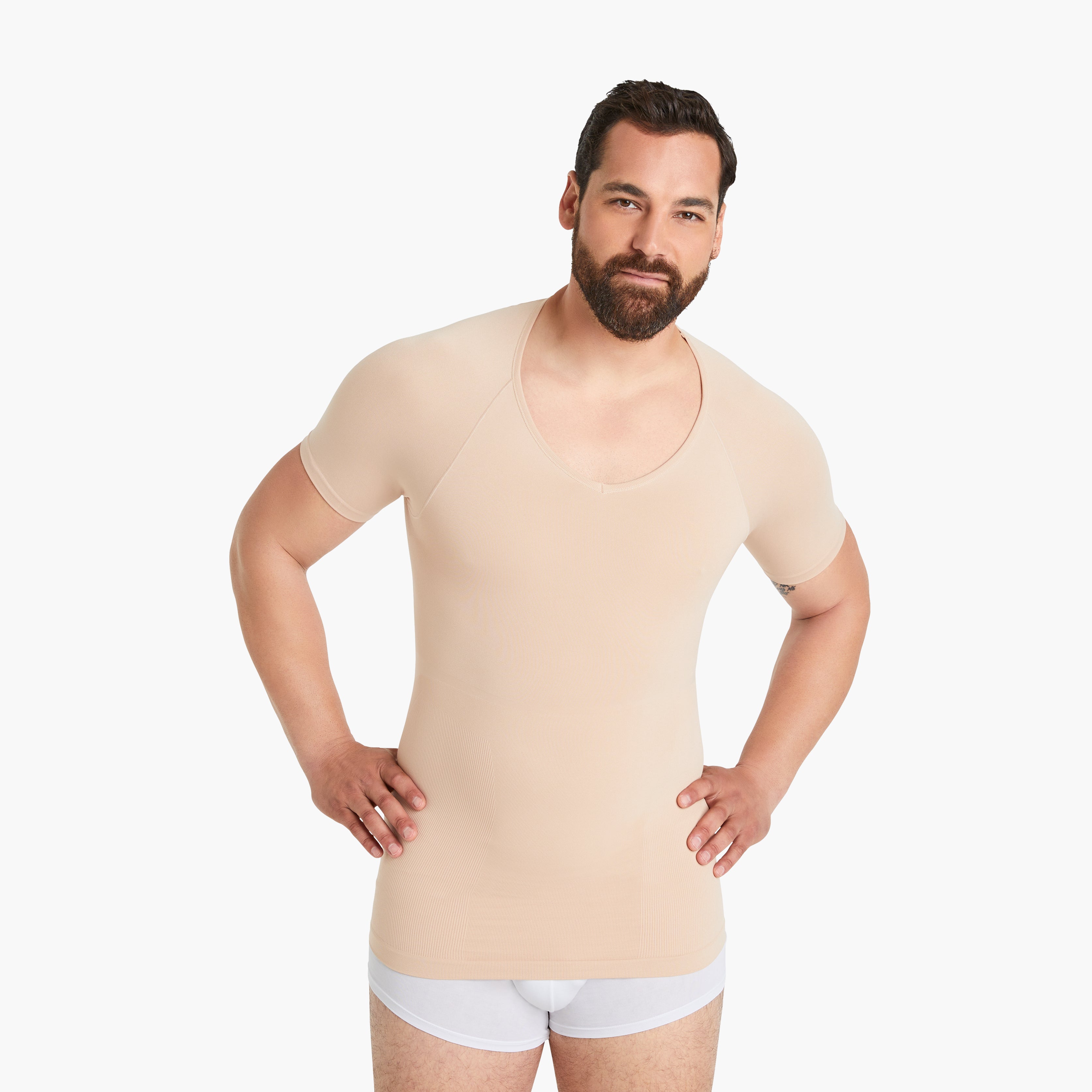 Selbstbewusster Mann mit Händen in der Hüfte trägt Größe XL des Seamless Shapewear Unterhemds für Herren in Hautfarbe. Entdecken Sie Komfort und Unterstützung in unserem nude Kurzarm-Kompressionsshirt. #farbe_nude