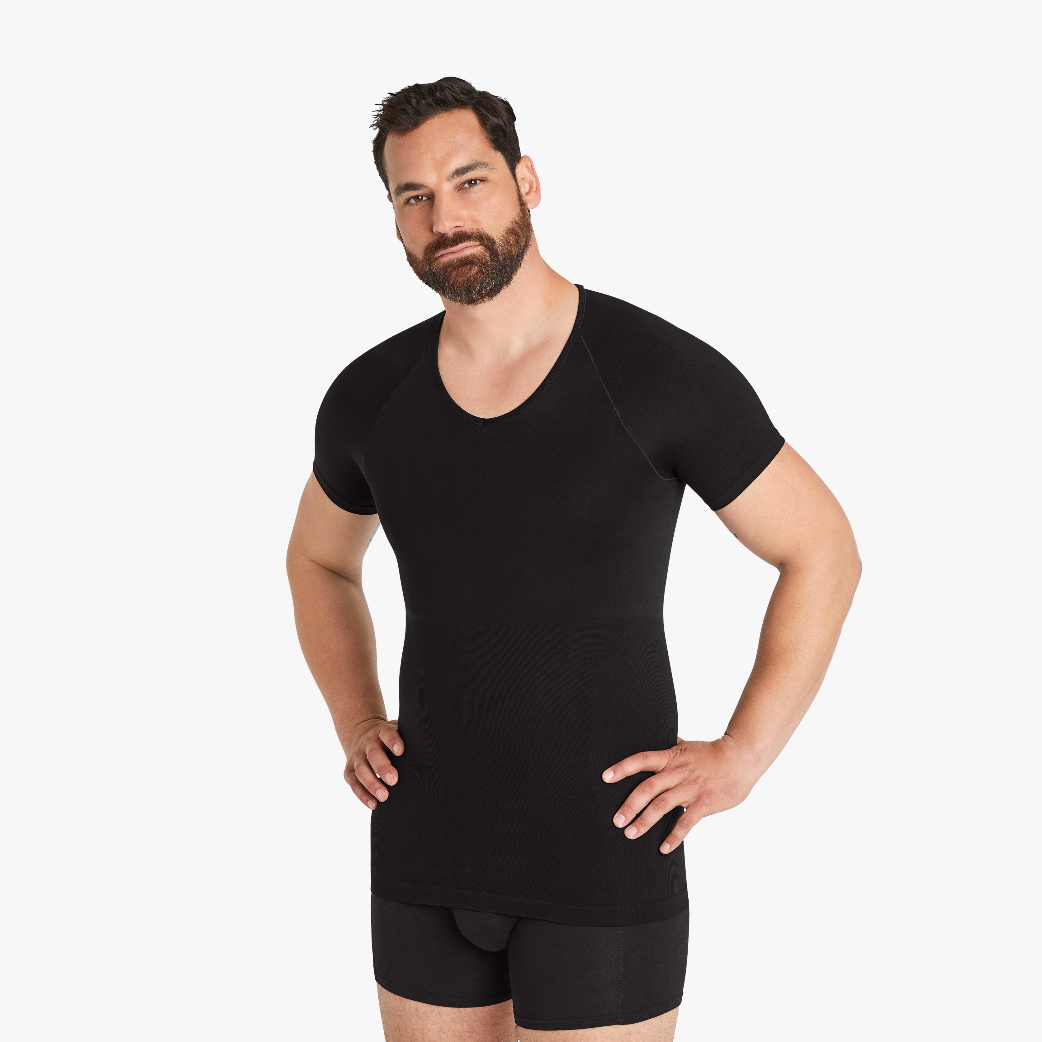 Selbstbewusster Mann mit Händen in der Hüfte trägt Größe XL des Seamless Shapewear Unterhemds für Herren. Entdecken Sie Komfort und Unterstützung in unserem schwarzen Kurzarm-Kompressionsshirt.#farbe_schwarz