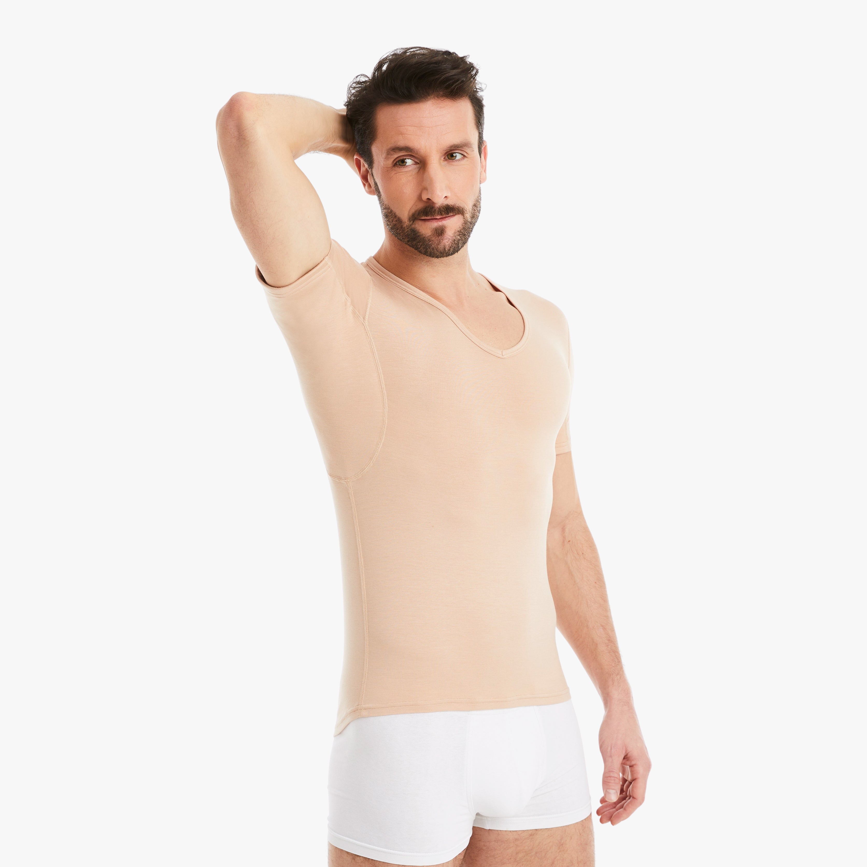 Mann trägt nude Anti-Schweiß Unterhemd Herren mit V-Abschnitt in Größe M. 100% Schutz vor Schweißflecken. Zertifizierter Tragekomfort, während er selbstbewusst die Achseln ohne Schweißflecken zeigt. #farbe_nude
